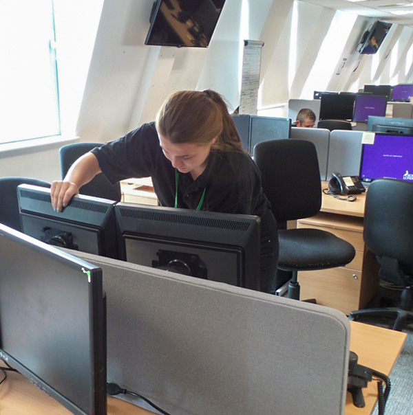 A woman disassembling several computers at once with the help of specialized tools. 