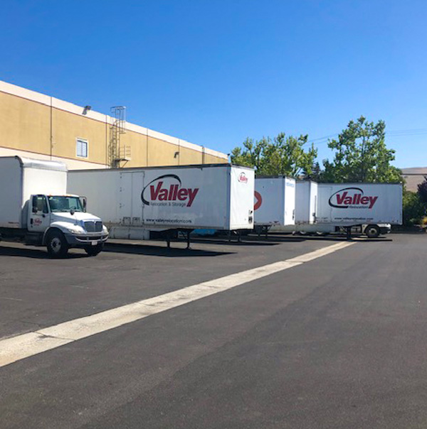 Several white and red valley relocation containers are parked in an open area.