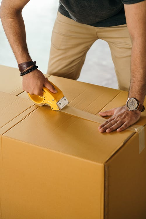 A mover taping up a box properly during relocation 