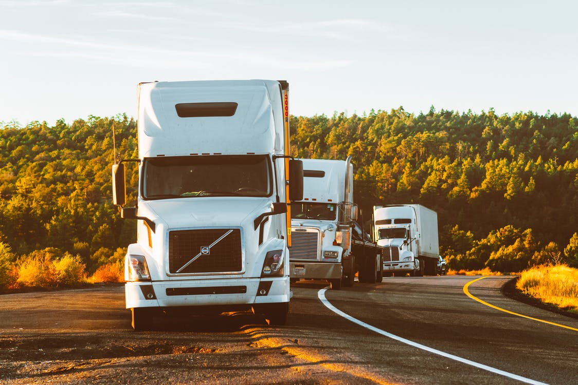 Moving trucks traveling on a road in a line