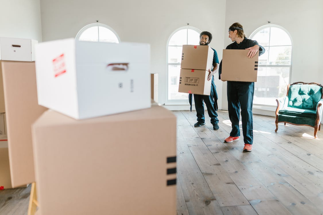 Two movers carrying large boxes