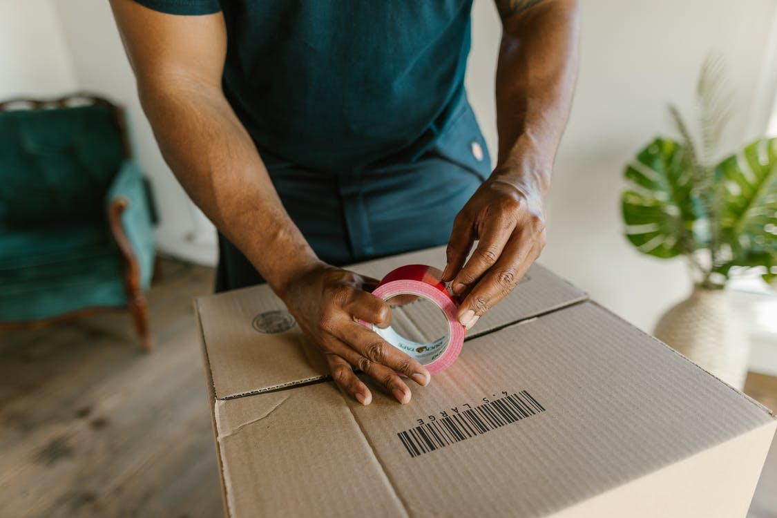 A professional mover putting tape on a box