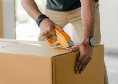 A person packing a cardboard box with tape.