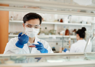 A laboratory professional using a dropper on a petri dish