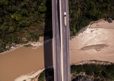 Aerial View of a Truck Affiliated with Commercial Office Movers Driving Over a Road Crossing a Stream