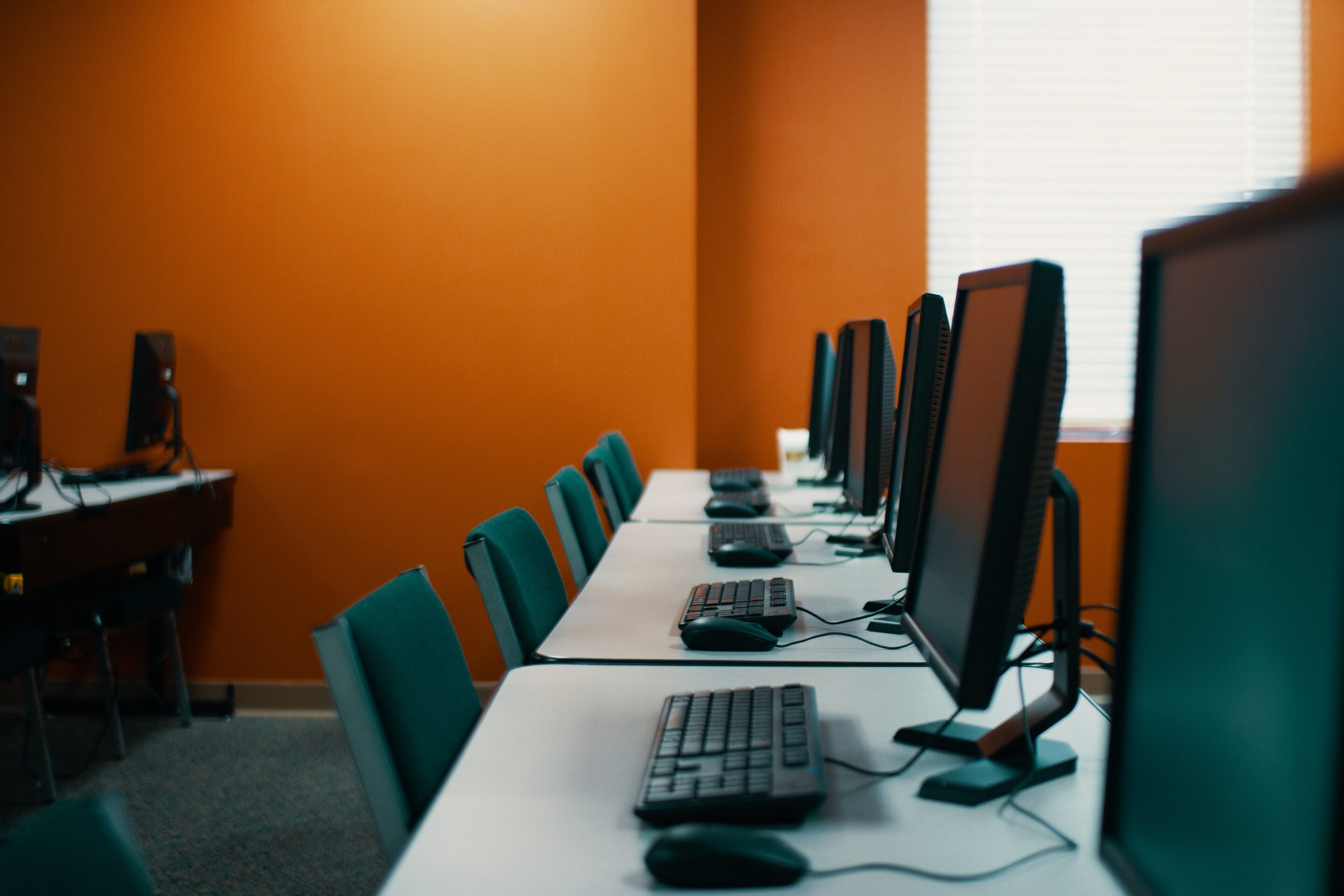 Several computers are lined up on a white desk