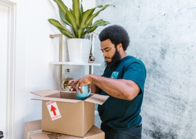 A person packing up things in a cardboard box