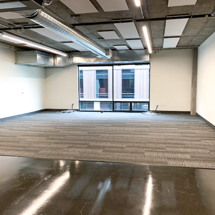 An empty office with glass windows and a tiled floor. 