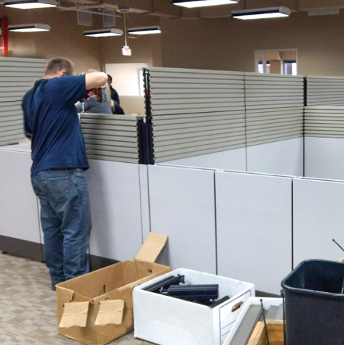  A person taking down a portable wall from office cubicles. 