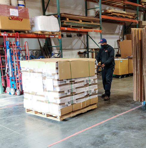 A person dressed in black carefully moves around packed boxes and more.