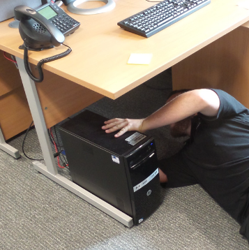 A person trying to unplug an IT equipment from under the table. 