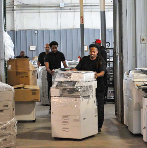 Two people moving a piece of equipment across the industry floor. 