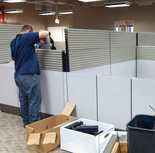 A man in a blue shirt disassembling an office cubicle