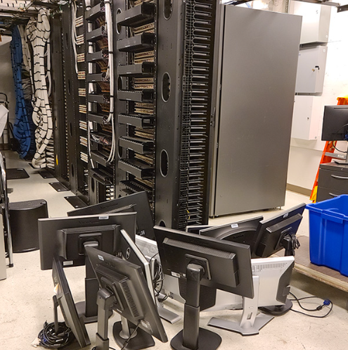  Several computer screens stacked together on the floor with several wires.