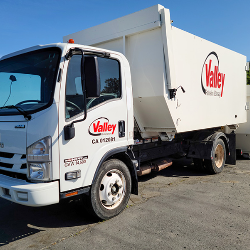 A white moving truck parked in the open air and an empty parking lot. 