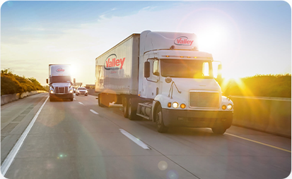  A white moving truck running across a freeway at sunrise. 