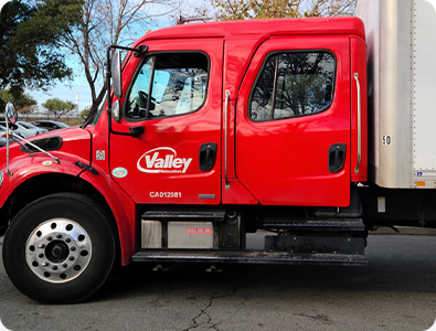 A red and white moving truck parked in an open space. 