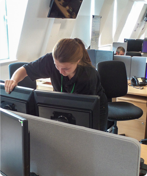 A woman working with several computer systems. 