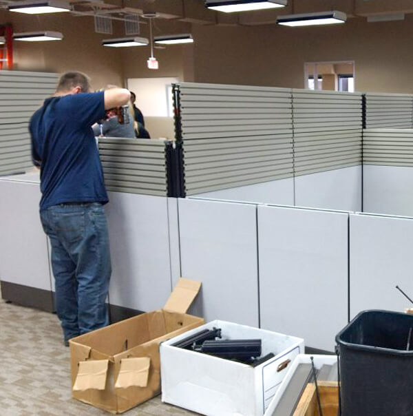 A man working on assembling a cubicle. 