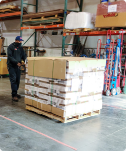 A person pushing a cart full of cardboard boxes.