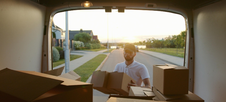 Movers Danville CA​ loading boxes into the back of a van in a residential neighborhood.