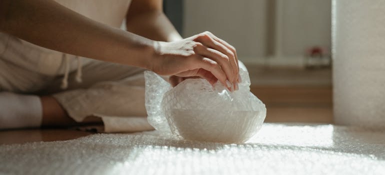 Person using bubble wrap to protect their belongings as a symbol of how to safely relocate your household.