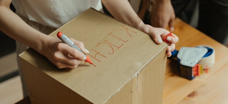 Woman labeling a moving box to safely relocate a household