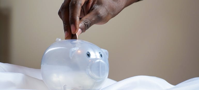 Person putting a coin in a piggy bank.