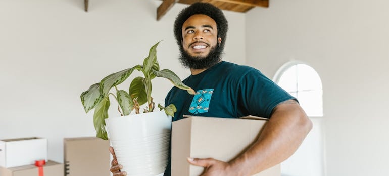 A member of movers Union City CA team holding a box and a potted plant.