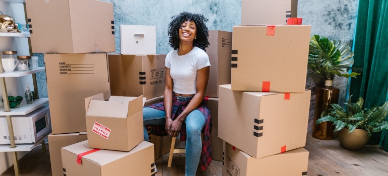 a woman sitting between boxes and thinking about International Moving Mistakes You Should Avoid 