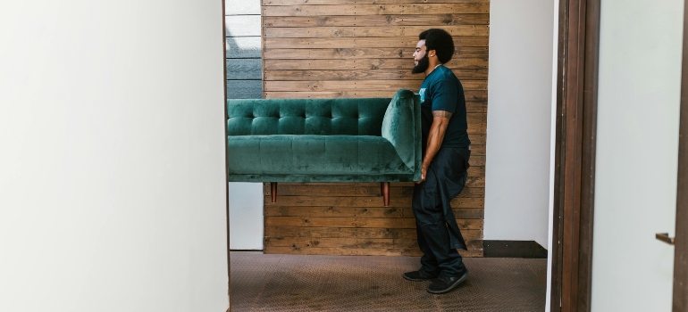 Mover lifting a green sofa, showcasing the strength and precision needed for efficient moves.