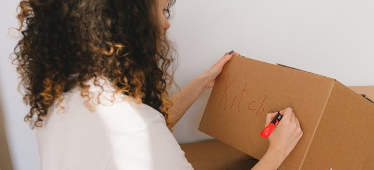 Woman labeling a cardboard box.