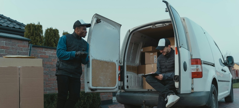 Two movers standing by a van, discussing logistics before starting a move.