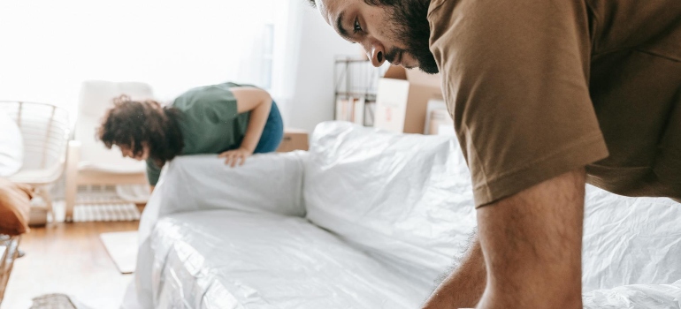 A couple placing a protective sheet over their sofa