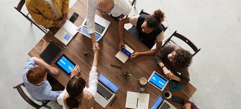 People doing a handshake at a meeting table.