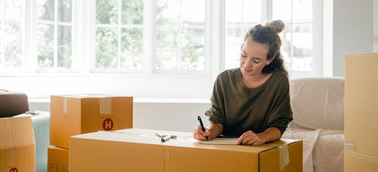 woman sitting among boxes and writing something