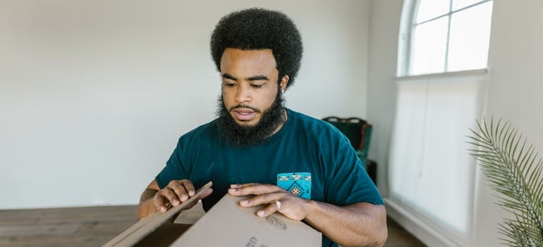 One of our commercial movers in the Bay Area closing a cardboard box.