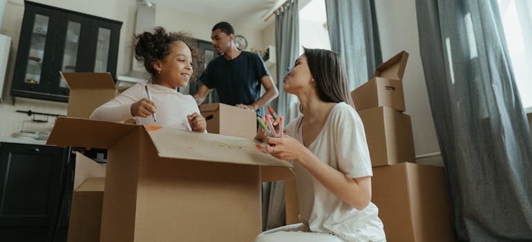 Parents packing moving boxes with their daughter to make moving with kids easier.