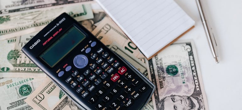 Calculator and notebook on paper bills.