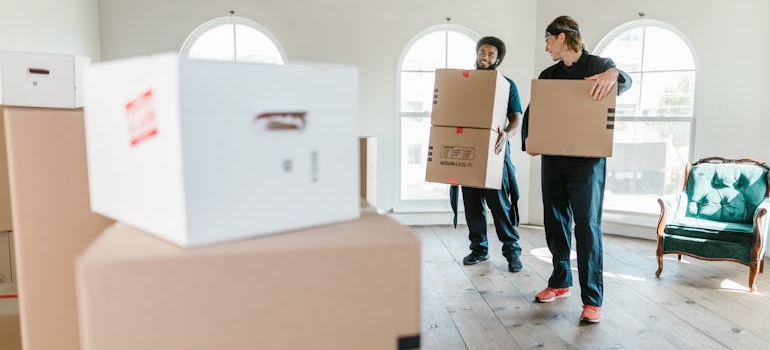 Two movers carrying big cardboard boxes.