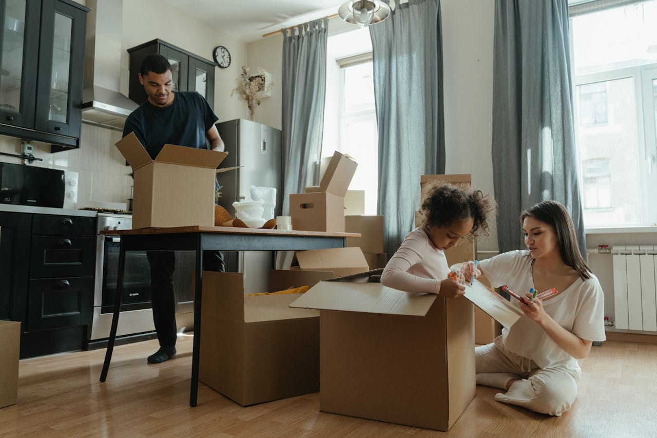 man, woman and little girl surrounded by movomg boxes