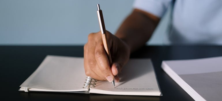 Man writing a moving to California checklist into his notebook.