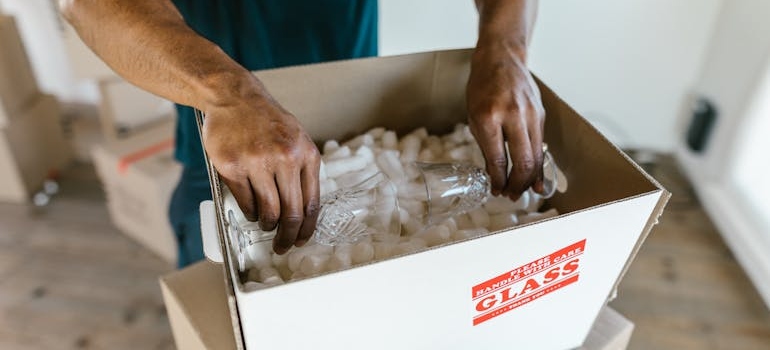 Man packing glasses in a padded box.