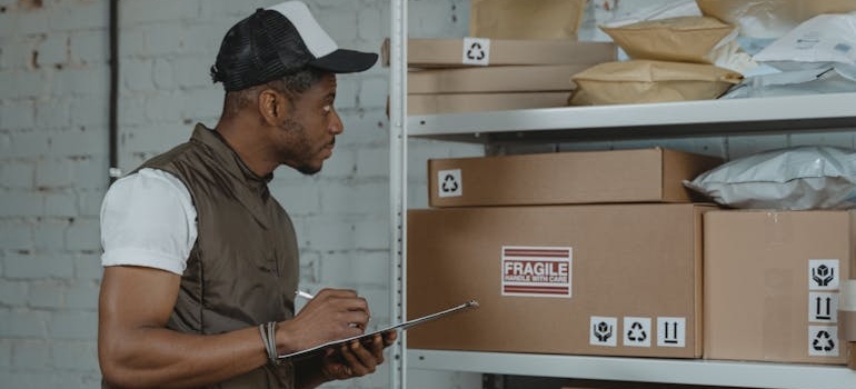 Man doing inventory of boxes in a warehouse.