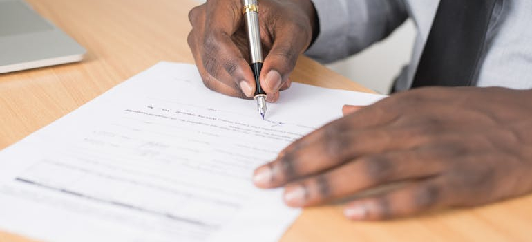 a person signing a document, so everything can be ready when Moving Abroad from California