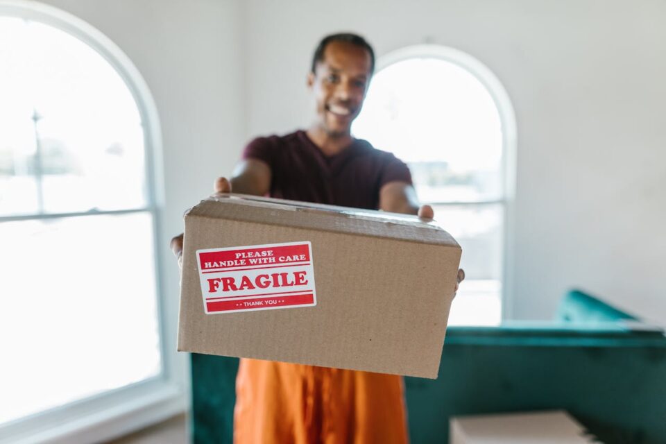 Man in Black Jacket Holding Brown Cardboard Box