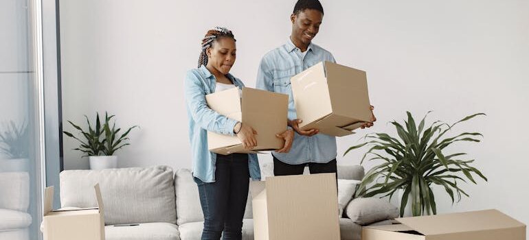 A Young Couple Holding Cardboard Boxes in a Living Room