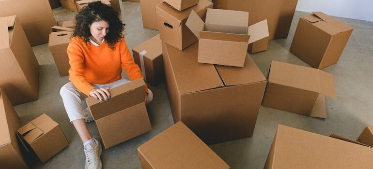 relocating lady packing carton boxes sitting on floor